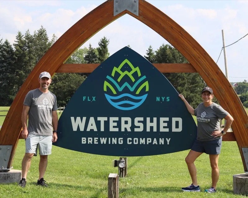 Ken and Lisa, founders of Watershed Brewing Company, at their Watershed sign